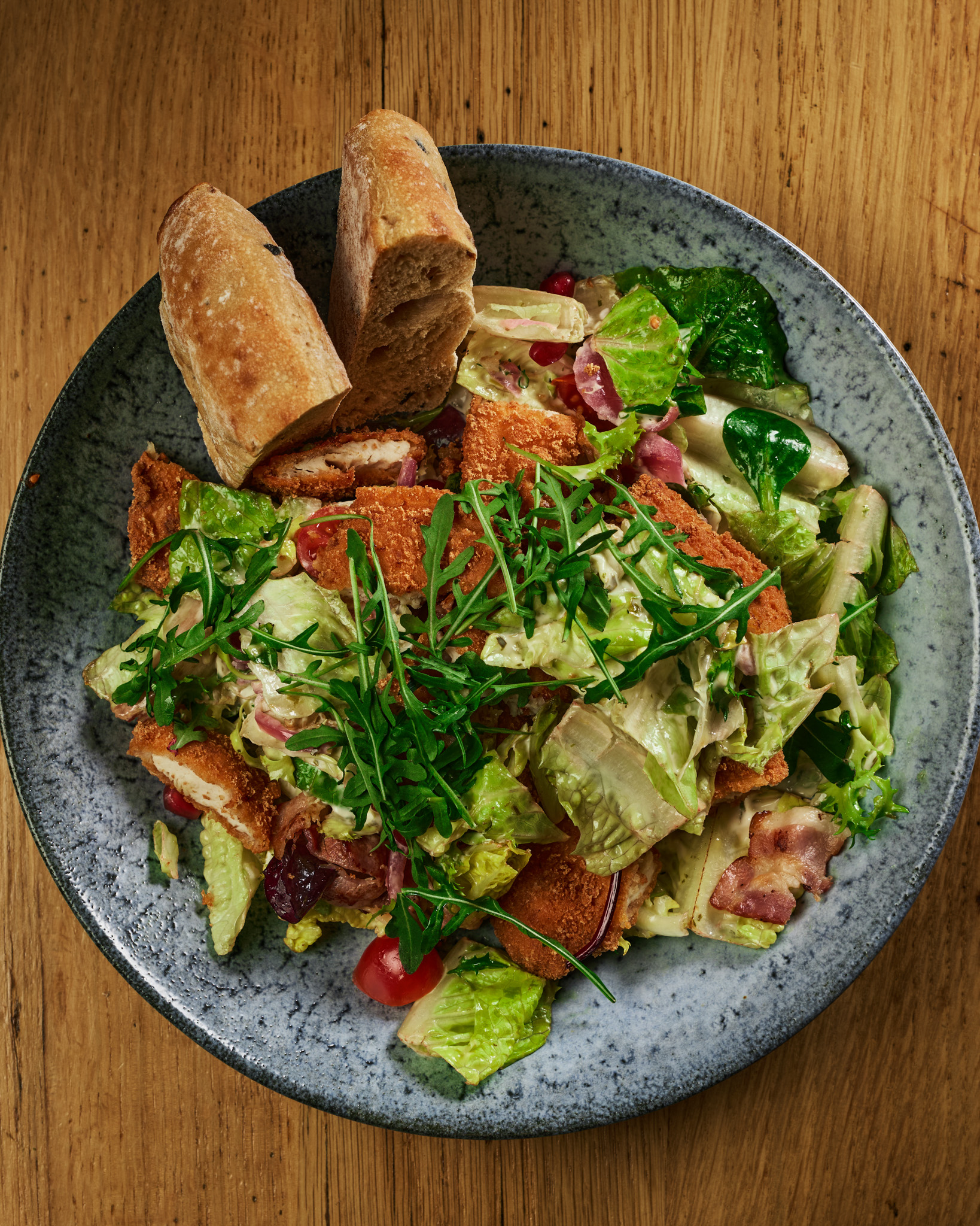 Salat med kylling og brød fotografert ovenfra på et trebord