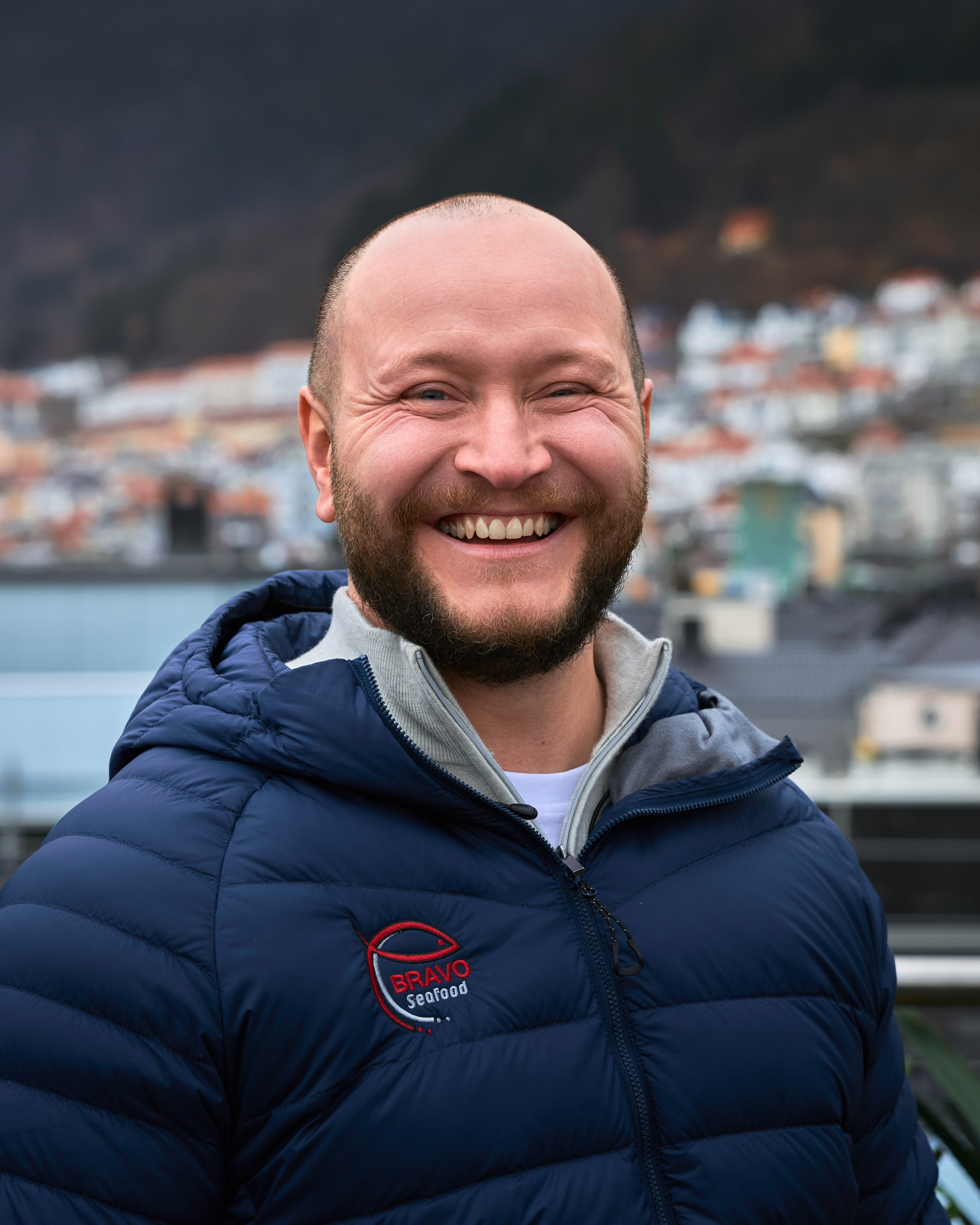 Smilende medarbeider hos Bravo Seafood med Bergen i bakgrunnen