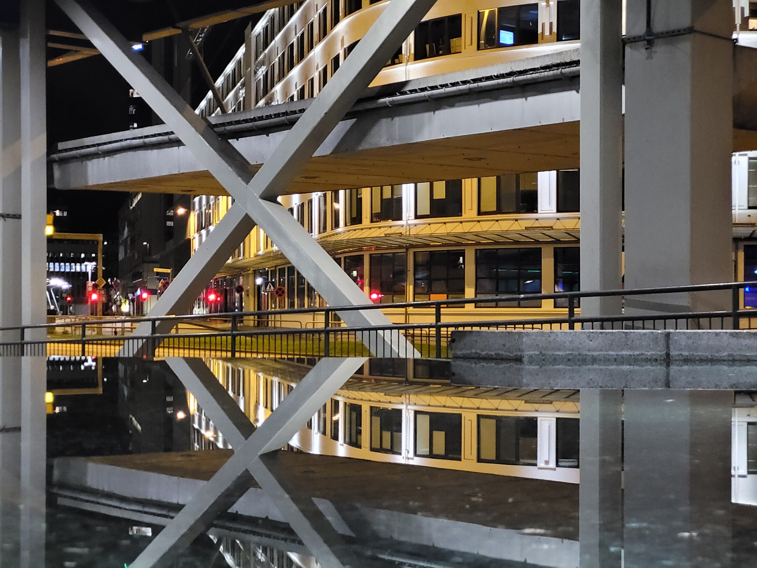 Nattbilde av moderne arkitektur og refleksjon i vann, med symmetrisk X-formasjon