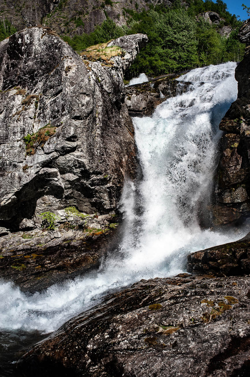 Kraftig fossefall omgitt av fjell og natur